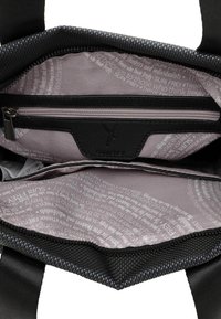 Black fabric bag interior with a zippered pocket, featuring a light purple lining with printed text in varying shades. Durable construction.