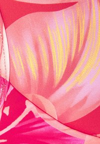 Helles pinkes und rotes Gewebe mit einem tropischen Blumenmuster, das aufwändige Nähte und geschwungene Nähte zeigt.