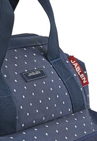 Bolso azul marino con lunares blancos, con un tejido texturizado, asas resistentes y forma rectangular. Etiqueta de la marca adjunta.