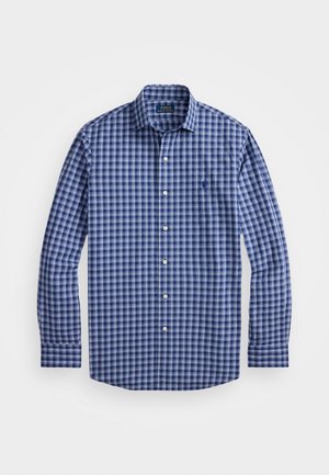 Chemise à manches longues à carreaux bleus avec un col boutonné, des boutons blancs contrastants et un petit logo brodé sur la poitrine.