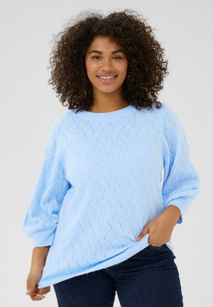 Pull en laine bleu clair avec un motif texturé, des manches larges et un col rond. Sa longueur dépasse légèrement les hanches.