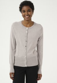 Cardigan gris clair en tissu tricoté doux, avec un col rond, des manches longues et des boutons argentés sur le devant.
