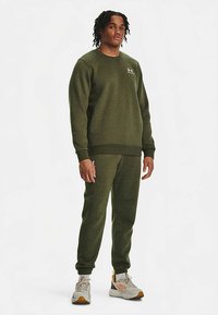 Set olivno zelene trenirke z majico iz teksturirane tkanine, z rebrastimi manšetami in pasom ter majhnim logotipom na prsih.