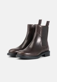 Brown leather Chelsea boots with smooth texture, elastic side panels, and pull tabs. Low block heel, rounded toe, and black rubber sole.
