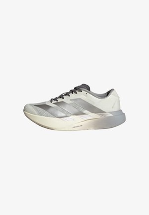 Zapatilla deportiva blanca y gris claro con cordones negros, tres franjas plateadas en el lateral y una suela gruesa y acolchada con la etiqueta "Lightstrike Pro."