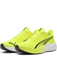 Scarpe sportive giallo brillante con tomaia in rete, dettagli neri, suola ammortizzata e design testurizzato, dotate di perforazioni e chiusura con lacci.