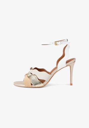 Sandaal met hoge hak en witte enkelriem, met geschulpte witte zijkanten en voorste banden in beige, wit en metallic goud.