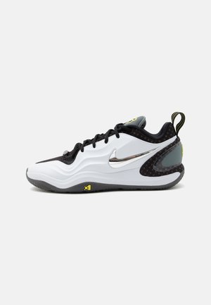 Belo-črni Nike copati s srebrnim logotipom, črnimi vezalkami, teksturirano podplatom in rumenimi poudarki, prikazani v stranskem profilu na belem ozadju.