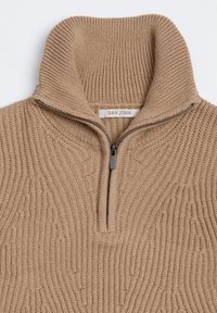 Beige strikpullover med høj krave, der har en halvlange lynlås, tekstureret mønster og et mærke med teksten "DAN JOHN" nær halsen.