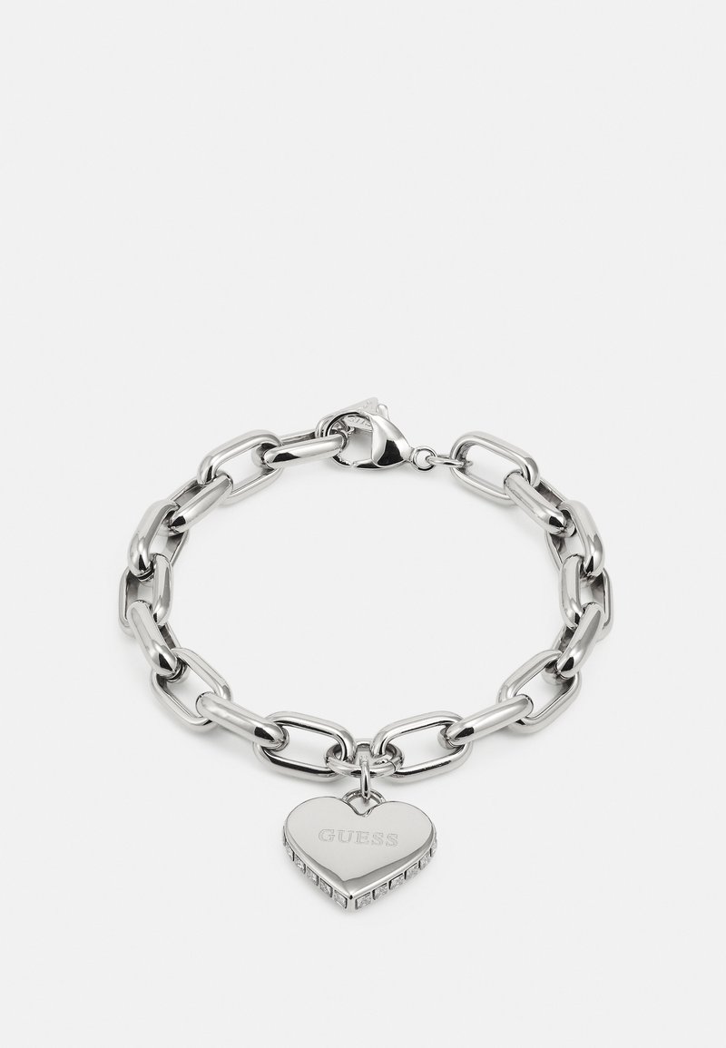 Bracelet à maillons en argent avec un pendentif en forme de cœur gravé "GUESS" et de petites pierres claires autour des bords.