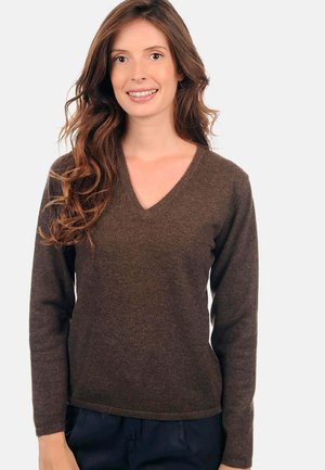 Un pull brun à col en V en matériau doux et texturé, avec des manches longues et une coupe décontractée, dont l'ourlet se situe au niveau des hanches.