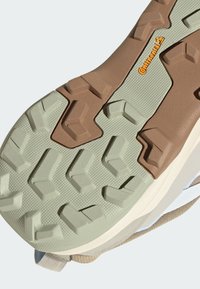 Gumová podešev s více směrovým vzorem; obsahuje zelené, hnědé a texturované prvky pro lepší trakci a grip.