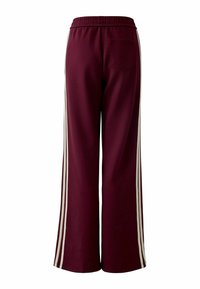 Bordeauxfarbene weit geschnittene Hose mit einem elastischen Bund. Sie verfügt über weiße seitliche Streifen und eine einzelne Gesäßtasche. Weicher, glatter Stoff.