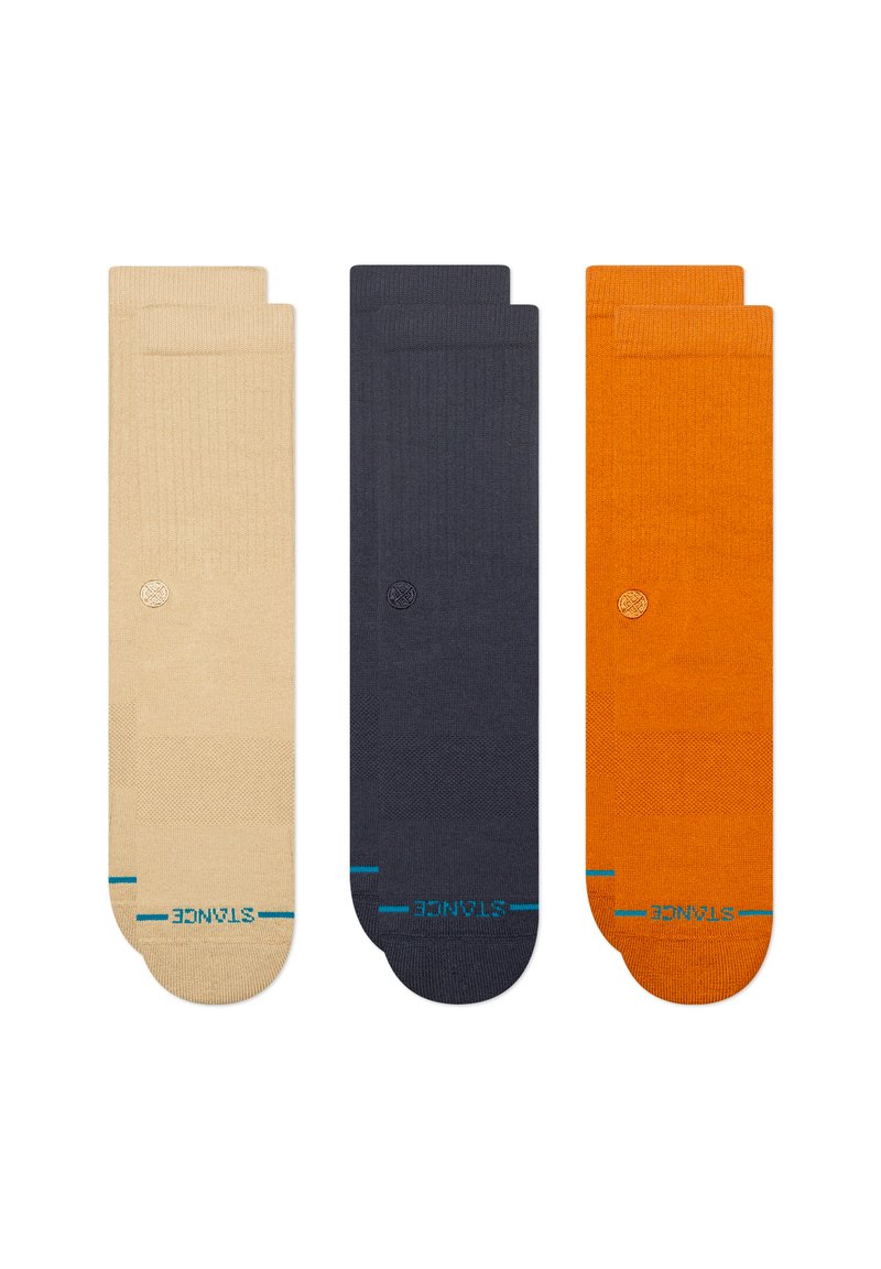 Drei Paar gerippte Socken: beige, dunkelblau und orange. Jede hat kontrastierende blaue Akzente und ein kleines Logo-Detail an der Seite.