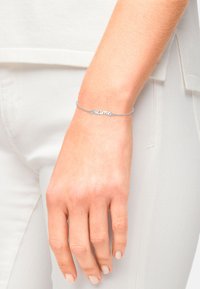 Bracciale d'argento con una delicata catena e la parola "mama" come punto focale. Presenta una finitura liscia e lucida.