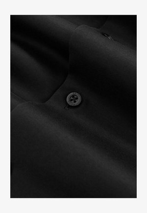 Svart tyg med en slät textur har en knapp med fyra hål och "REISS" präglad. Den övergripande designen är strömlinjeformad och minimalistisk.