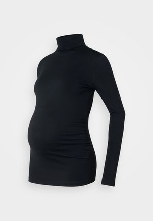 Haut à manches longues noir à col roulé en tissu extensible, conçu pour accueillir un ventre de femme enceinte, avec des détails de fronces sur les côtés.