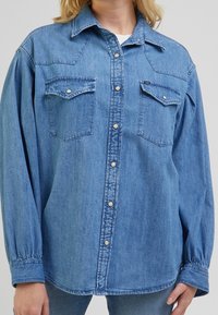 Hellblaus Denim-Hemd mit langen Ärmeln, Knopfleiste, zwei Brusttaschen und klassischem Kragen. Bietet einen lockeren Schnitt und strukturierte Stoff.