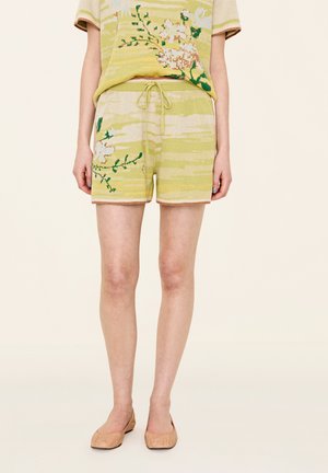 Lichtgele shorts met een zachte textuur, voorzien van bloemenpatronen. Koordsluiting in de taille en contrasterende afwerking. Geschikt voor casual draag.