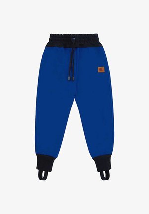 Niebieskie spodnie dresowe dla dzieci z czarnym elastycznym pasem, sznurkiem do regulacji, ściągaczami na kostkach oraz paskami na stopy, z małą brązową naszywką z logo.