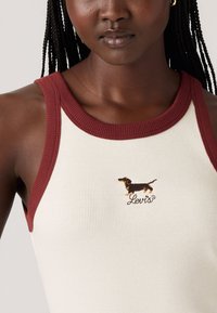 Ribbestrikket tanktop i kremfarge med vinrøde detaljer. Har en brodert dachshund i brunt og svart og "Levi's"-logoen på brystet.