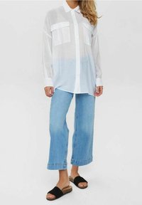 White, semi-transparent button-up shirt with two chest pockets, paired with light blue wide-leg jeans and black slide sandals.