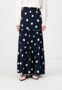 Tamsiai mėlyna maxi sijonas su taškeliais, su trimis sluoksniais ruffles, elastine juosta, sklandžiu paviršiumi ir baltais apskritimais.