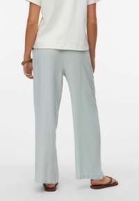 Lichtblauwe linnen broek met een wijd pijpontwerp, met een ademende textuur. Draag het met een losse witte blouse en bruine sandalen.