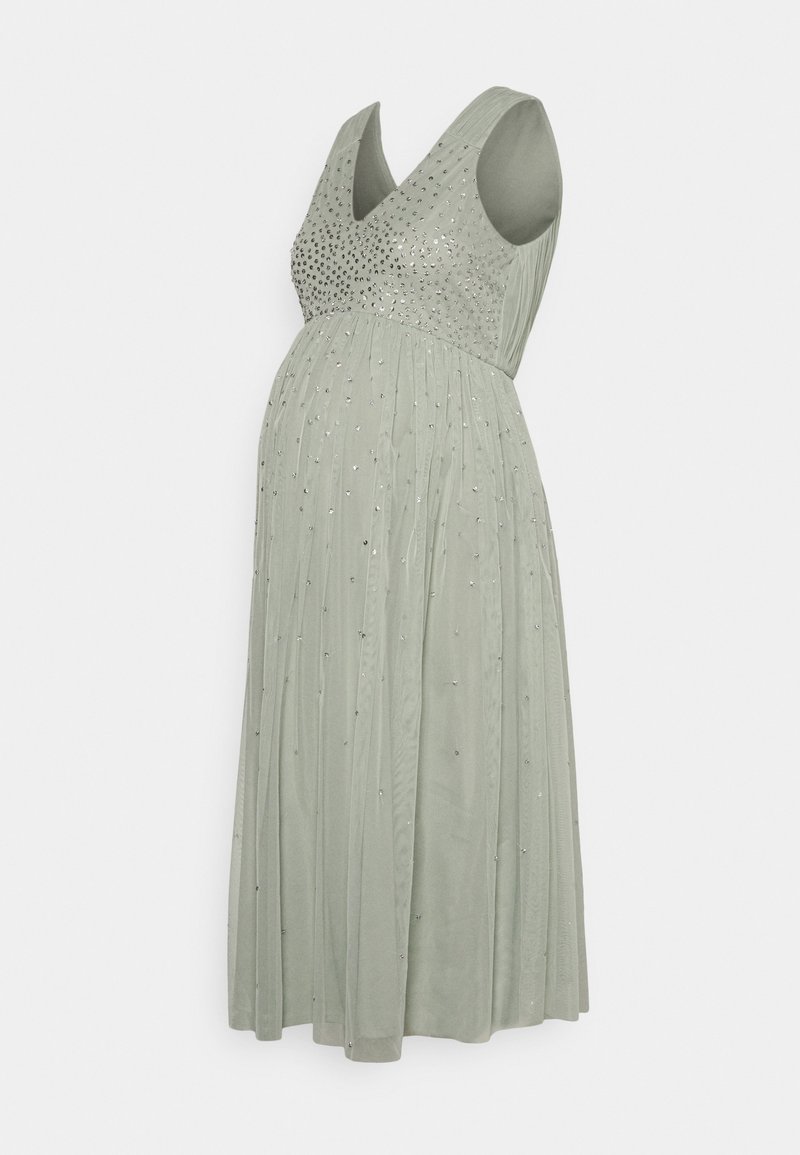 Vestido de maternidade em suave verde sálvia, com decote em V e corpete adornado com detalhes prateados. Saia pregueada que flui suavemente.