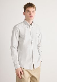 Gestreepte button-up shirt in lichtgrijs en wit, met een kraag, lange mouwen en een klein geborduurd logo op de borst.