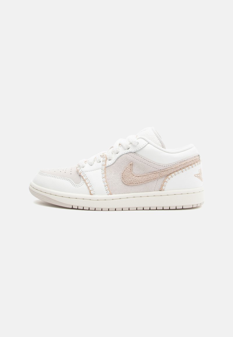 White sneaker with suede and leather material, pink accents, lace-up design, rounded toe, and logo on the side with textured detailing.