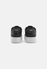 Sneaker in pelle nera con una superficie esterna testurizzata e suole in gomma bianca. Presenta un marchio sul tallone e un collare imbottito per il comfort.