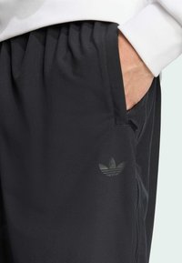 Svarta träningbyxor i smidigt material med elastisk midja och sidoficka. Har en subtil, mörk tryckt logotyp på låret.