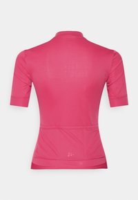 Dres na kolo s krátkými rukávy v jasně růžové látce. Má vysoký límec, zadní kapsy a elegantní, přiléhavý střih. Hladká textura.