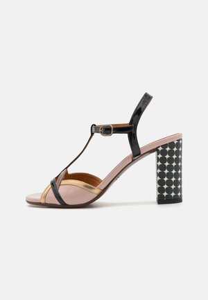 Sandalo con tacco alto in pelle nera, dorata e rosa tenue. Presenta un design a T-strap con un tacco a blocco decorato e una cinghia per la caviglia regolabile.