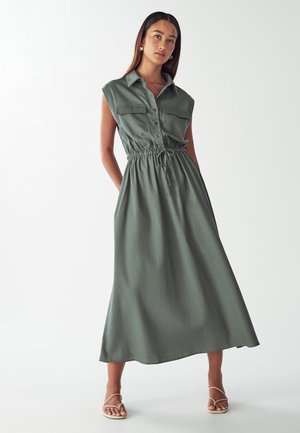 Green, sleeveless maxi dress with button front, two chest pockets, and drawstring waist. Smooth fabric with a relaxed silhouette.