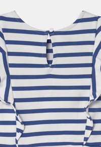 Indumento a strisce bianche e blu con scollatura arrotondata, dotato di una piccola chiusura a bottone e un'apertura a forma di chiave sul retro.