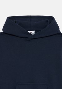 Haut à capuche en coton bleu marine avec une poche avant, capuche ajustable à cordon, et étiquette visible à l'intérieur du col. Texture lisse.