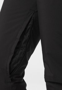 Pantalones negros con cremallera lateral y forro de malla, textura de tela suave y diseño ajustado para un uso funcional.