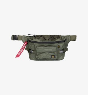 Maslinasto zelena tkanina fanny pack sa prednjim patentnim džepom, mrežastim detaljima, podesivim trakama i dekorativnom crvenom oznakom.