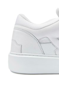 Valkoiset lenkkarit, joissa on teksturoitu nahkaosa, sileät yksityiskohdat, pehmustettu nilkkaosa ja paksu valkoinen kumipohja.