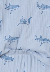 Light blue ribbed fabric with a pattern of dark blue sketched sharks and a visible waistband seam.