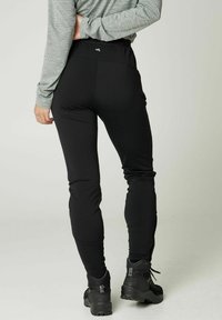Zwarte legging met een gladde textuur en een taps toelopende pasvorm, voorzien van een elastische tailleband en ontworpen voor veelzijdige actieve kleding.