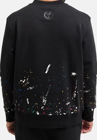 Černá mikina s barevnými skvrnami, kulatým výstřihem, žebrovanými manžetami a lemem a logem na zadní straně. Hladká, strukturovaná tkanina.