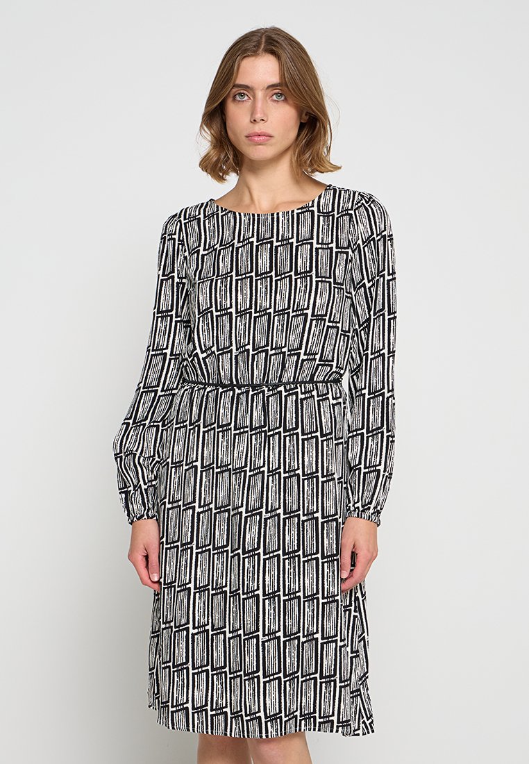 Vestido de manga larga con un patrón geométrico en blanco y negro, escote redondo y cintura elástica para un silueta ajustada.