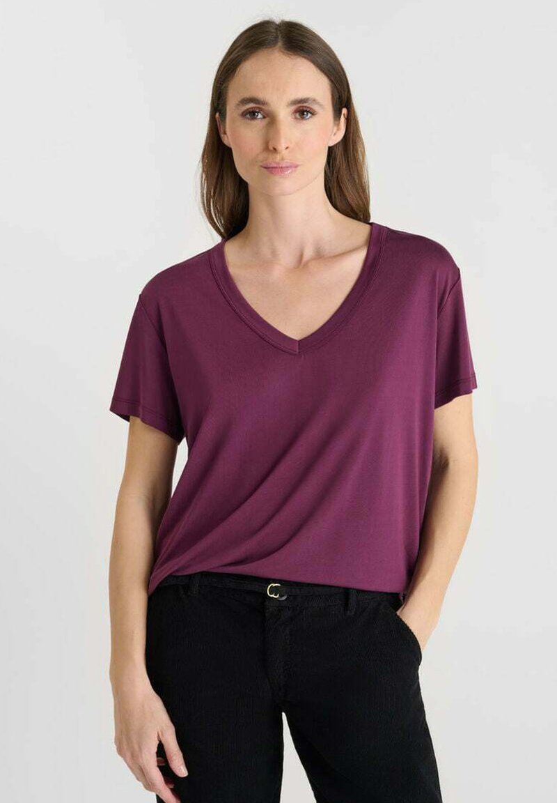 V-hals, T-shirt met korte mouwen in diep bordeaux stof, gedragen met zwarte gestructureerde broeken. Eenvoudig ontwerp met een losse pasvorm.