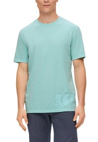 Lichte teal-kleurige T-shirt met korte mouwen, gemaakt van katoen. Heeft een ronde halslijn en een subtiele grafische print op de linkerbovenhoek.