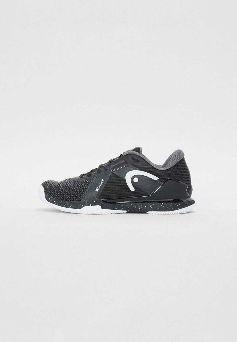 Chaussure de sport noire avec une tige en mesh texturé, des accents blancs et gris, une semelle intermédiaire noire mouchetée et une semelle extérieure en caoutchouc blanc.