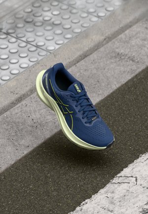 Scarpa da running blu navy con tomaia testurizzata, suola verde chiaro e dettagli riflettenti. Dotata di chiusura con lacci e sezioni perforate per favorire la traspirazione.