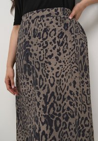 Leopard print maxi skirt in beige fabric, featuring dark navy spots, a high waistband, and side pockets, with a textured finish.